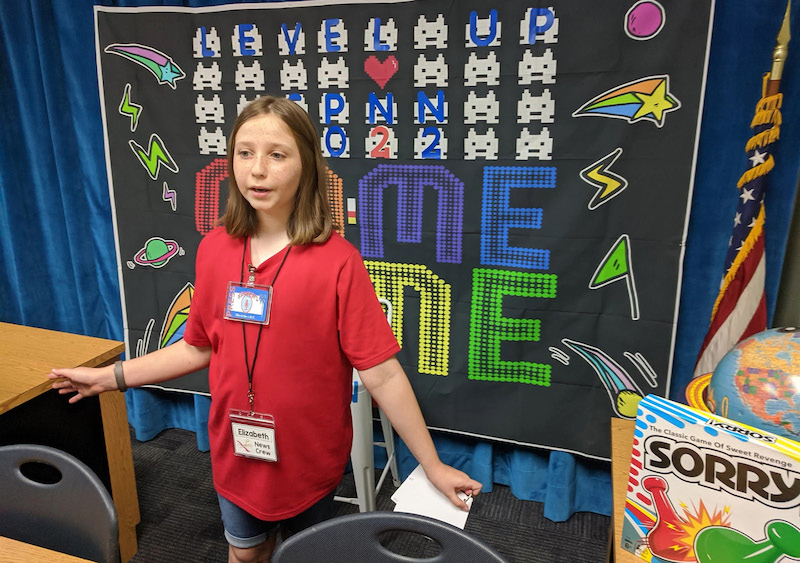 Elizabeth, a member of the Sabal Palm Elementary School student news team (Jacksonville, FL), shows off the facility’s anchor desk,  used for online broadcasts